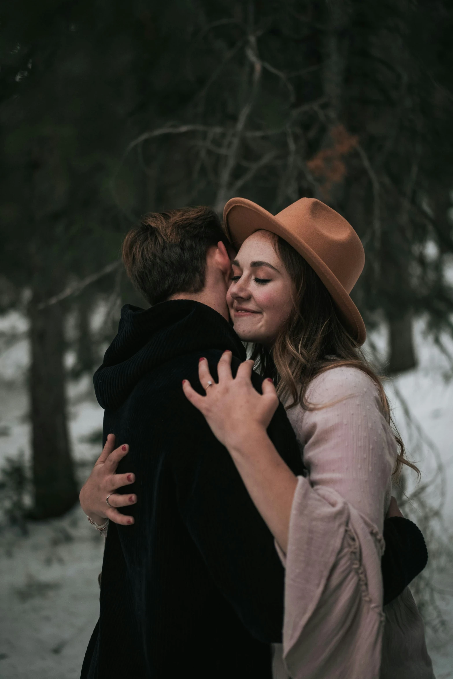 a man and woman hugging in the woods