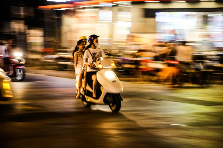 a couple riding on a scooter down a street