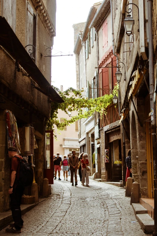 an old stone city street with people walking down it