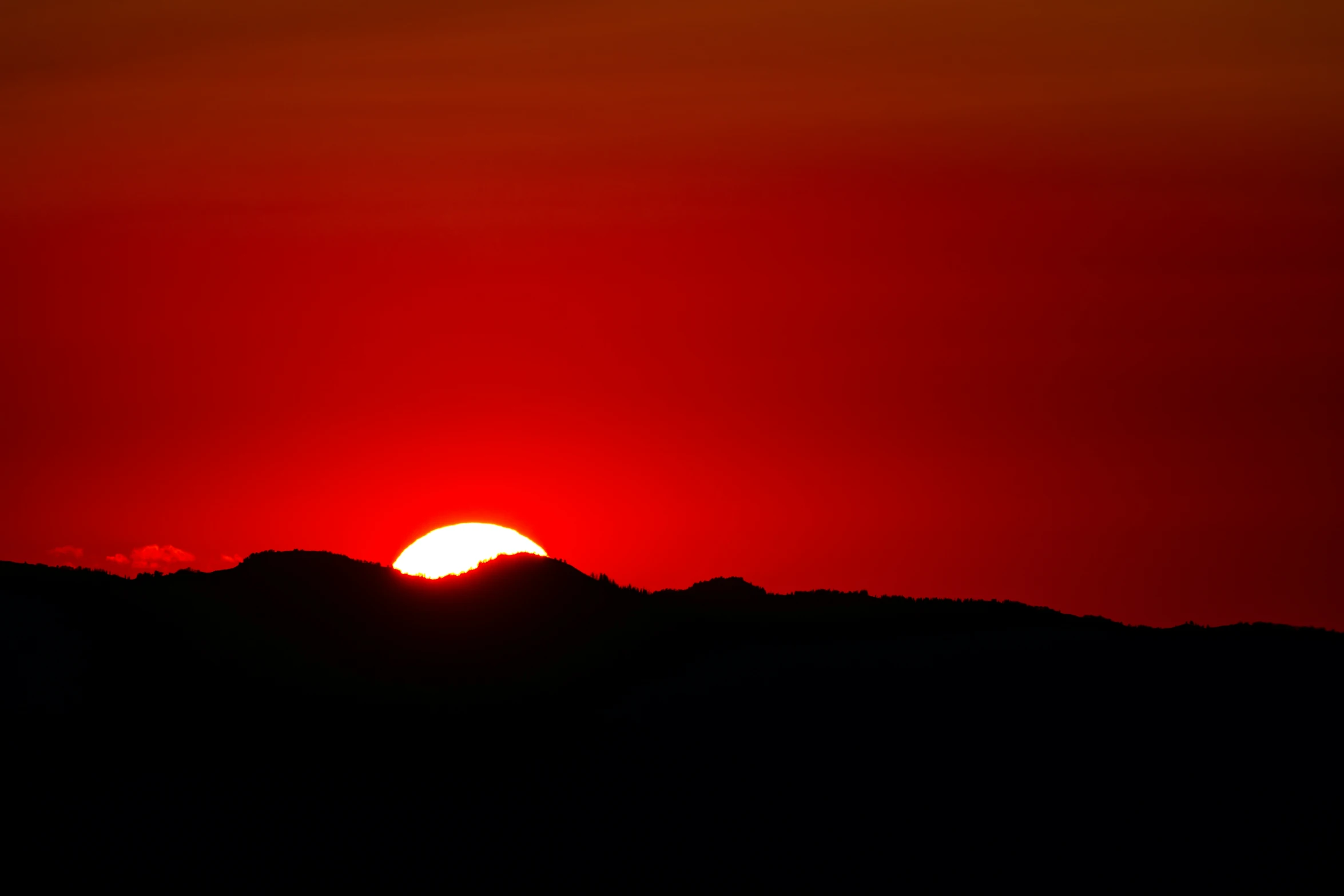 a red and black sky with the sun going down