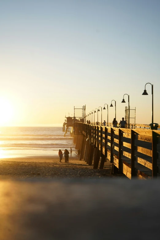 two people are standing by the ocean at sunset