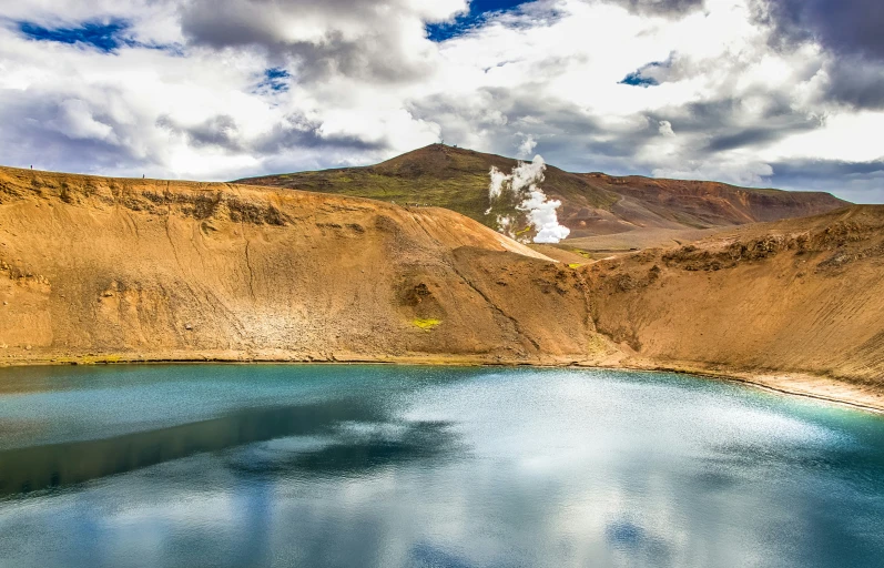 mountains are next to a body of water and clouds