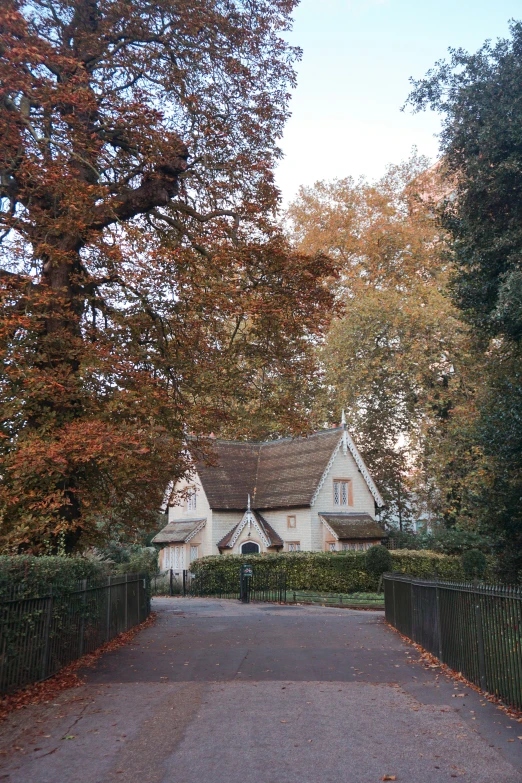 a large gate in front of a house with fall leaves on the trees