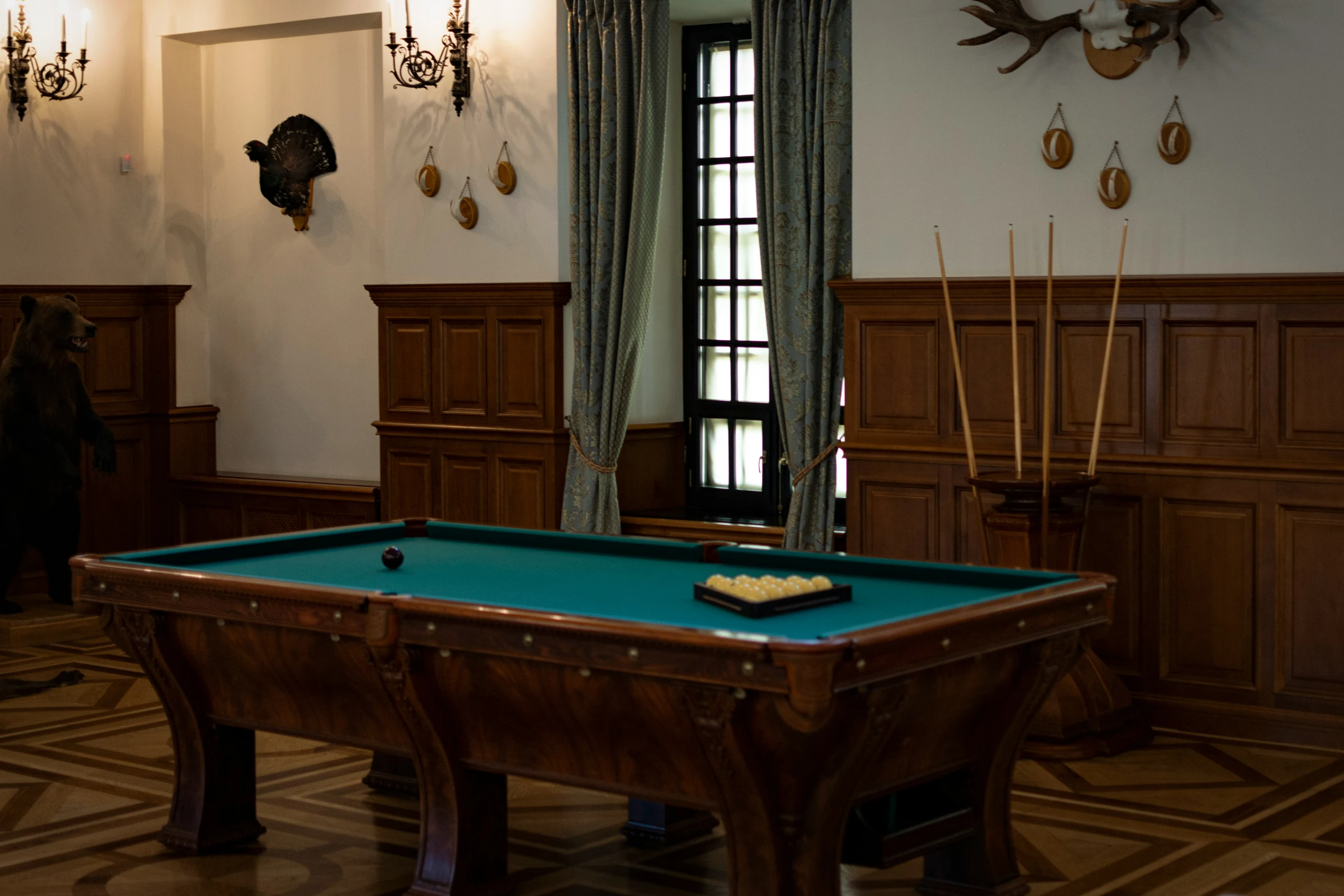 a pool table in the middle of a room with deer heads on the wall