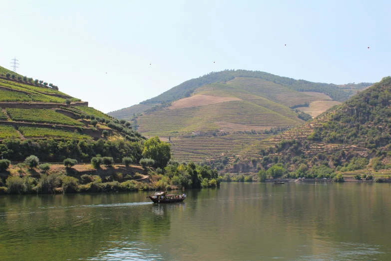 a fishing boat floats down a river with the mountains in the background