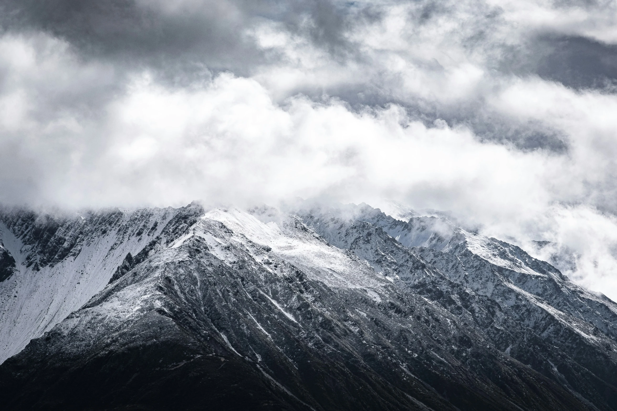 a very dark mountain surrounded by clouds