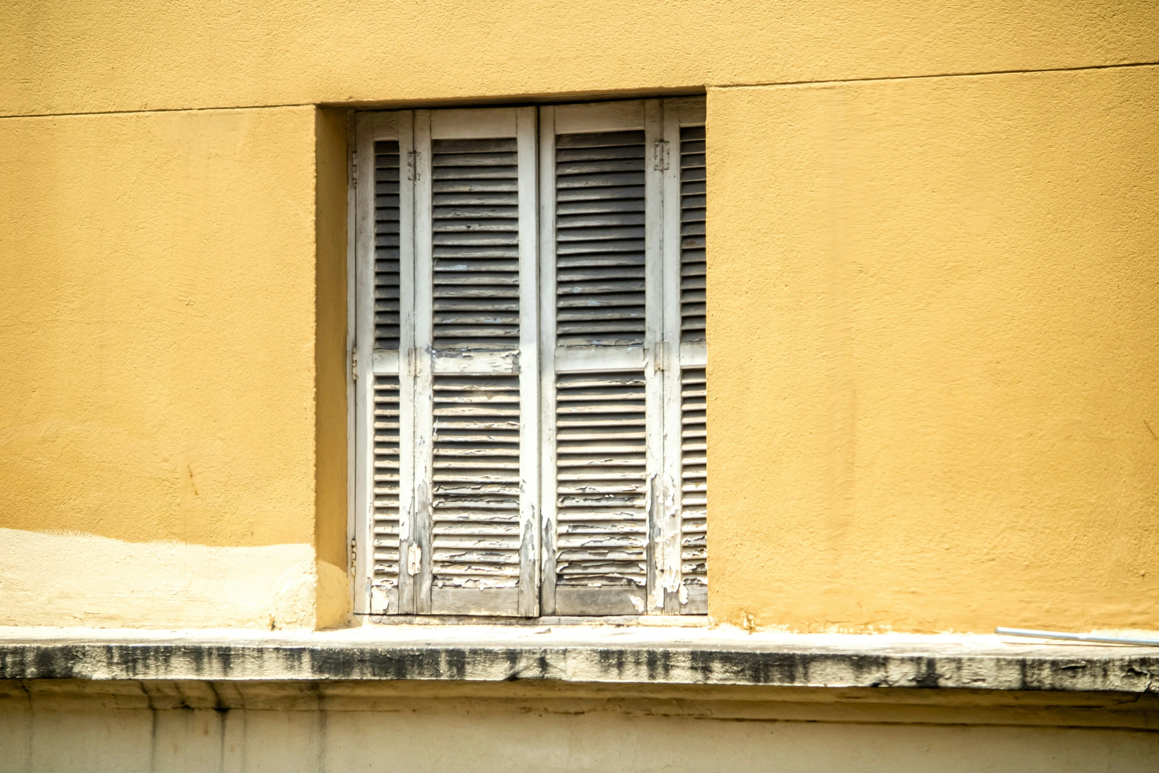 a yellow wall with a window and bars on the front