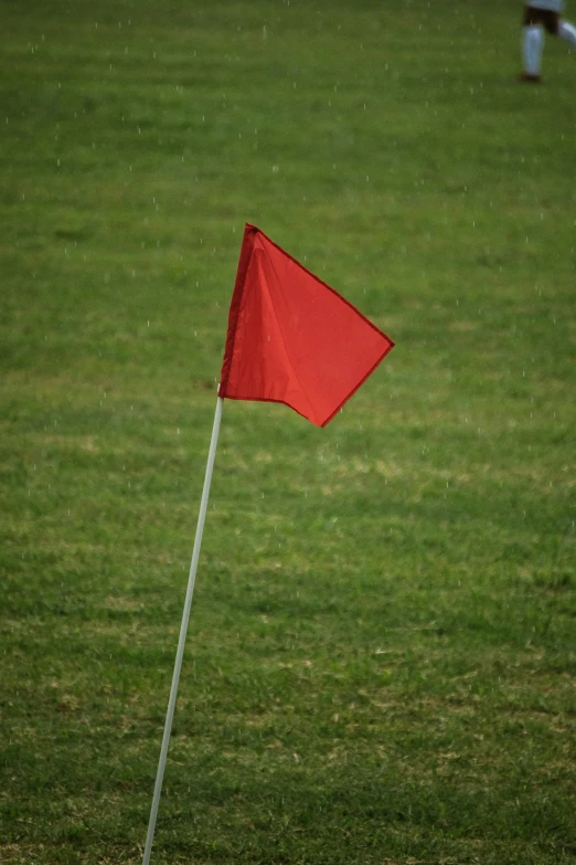 a red flag flying in the air next to green grass