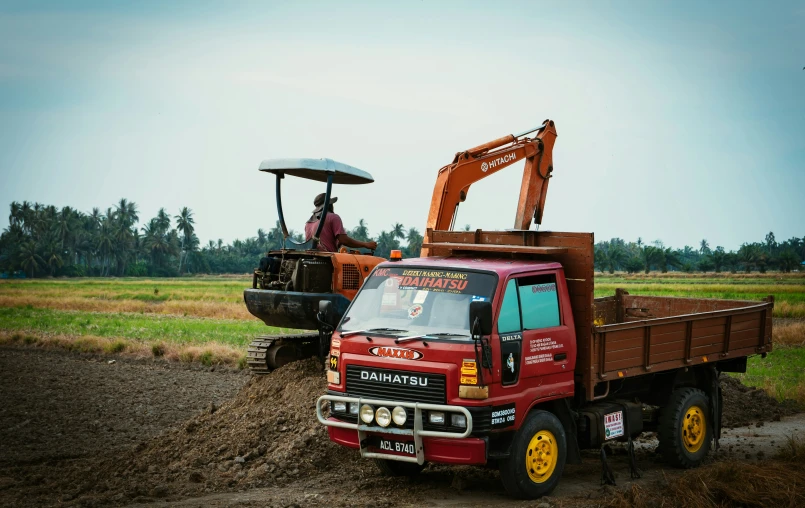 a red truck parked next to a red tractor