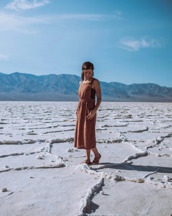 a woman in a brown dress standing on some ed ground