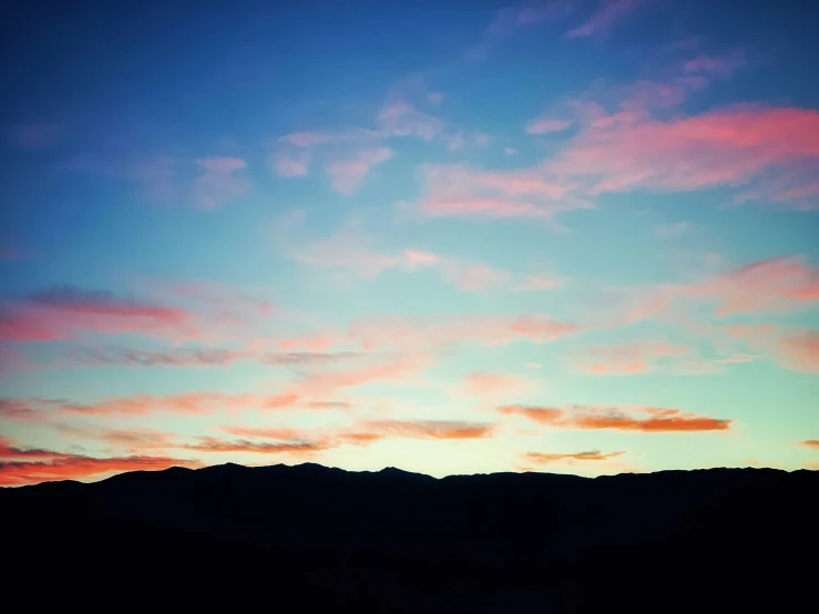 the sky has a pink hue as a airplane flies by