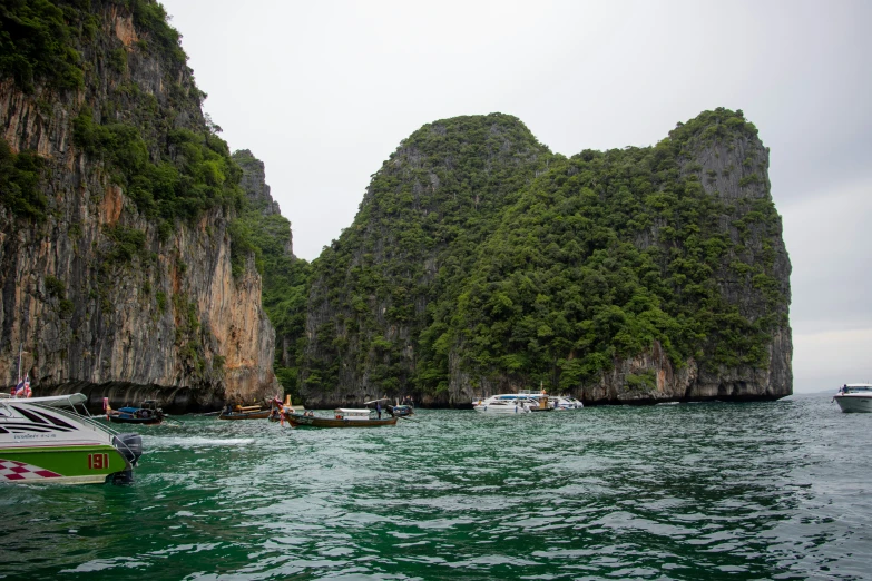 a number of boats on a body of water near many large rocks