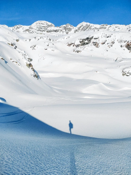 a lone figure on snow covered ground near mountains