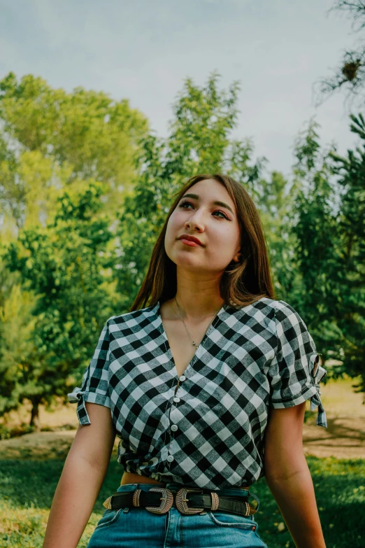 a girl standing in grass in front of trees