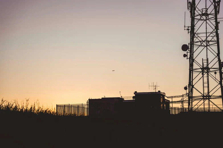 the silhouette of an industrial tower and a radio signal