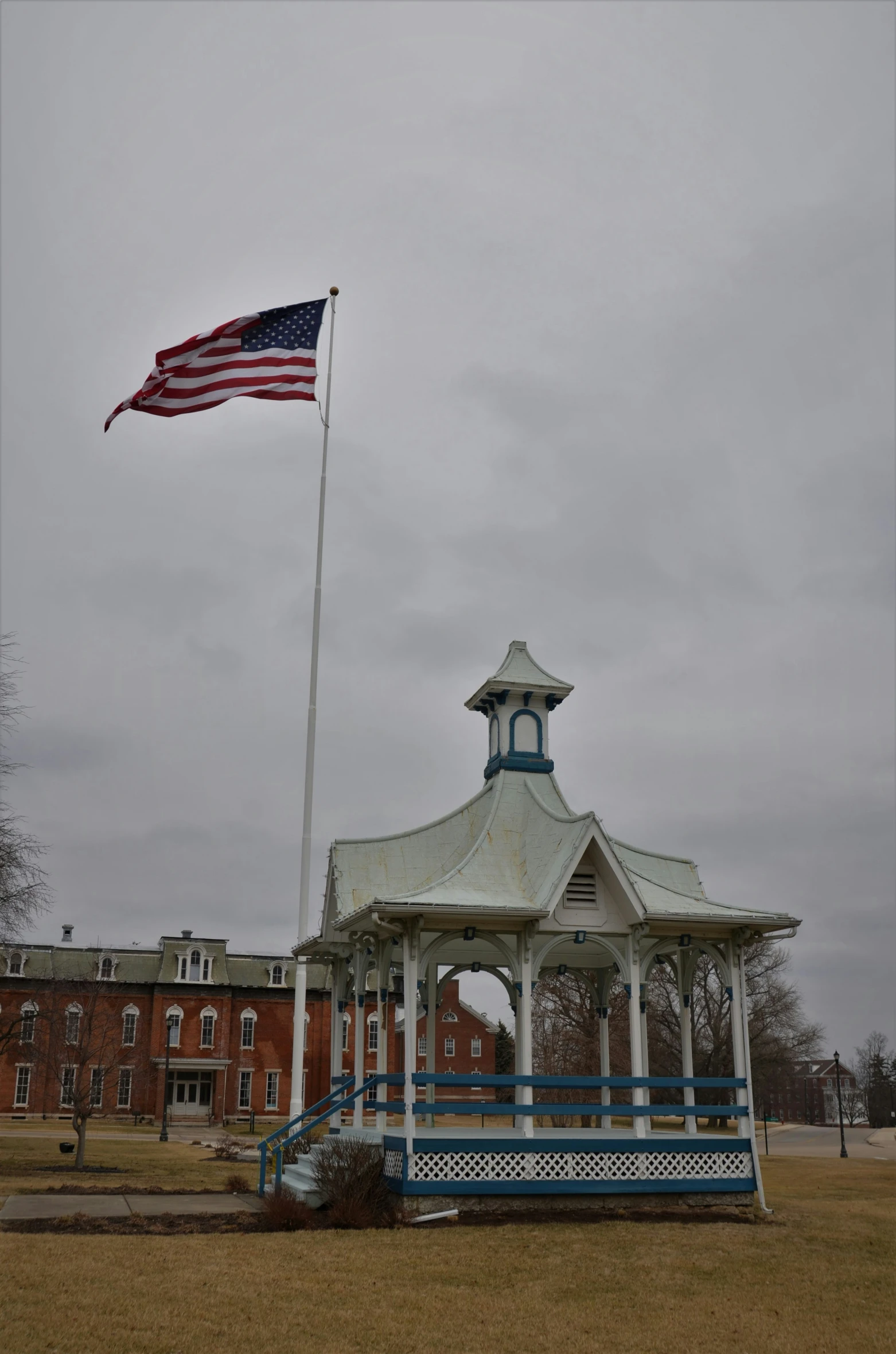 a gazebo sitting in the middle of a grass covered field next to a flag