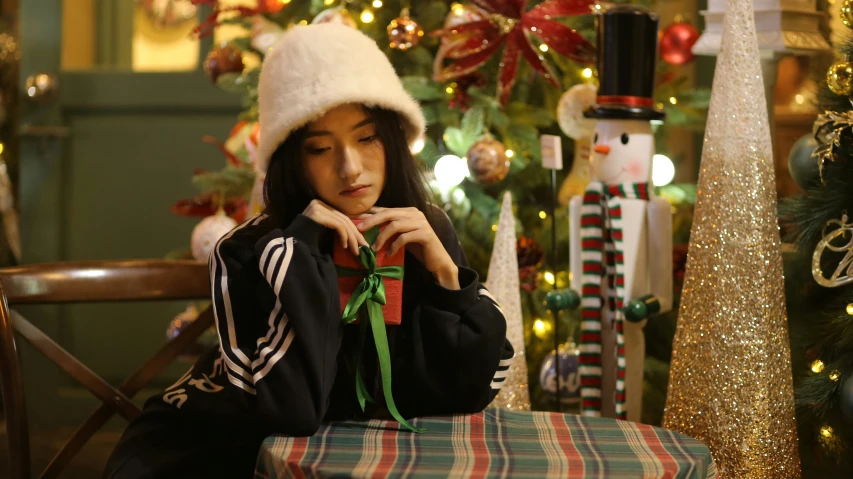 a young person sitting next to a decorated christmas tree