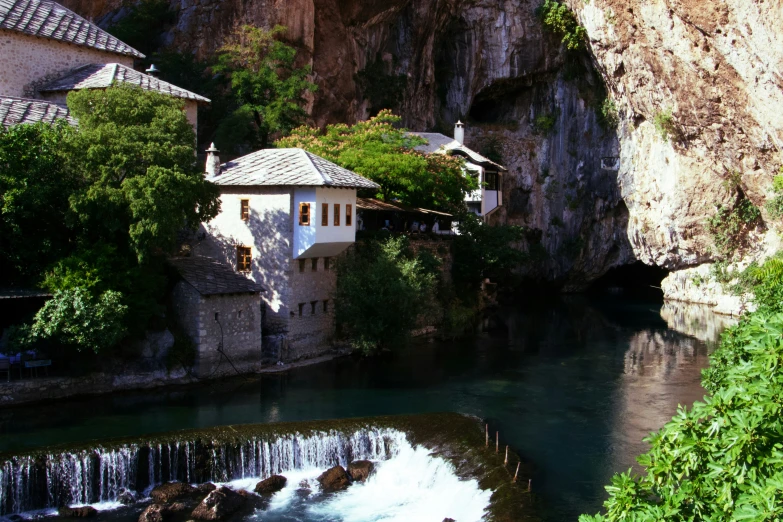 a couple of houses next to a stream in a valley