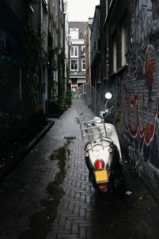 a motorcycle is parked along a wall covered alley