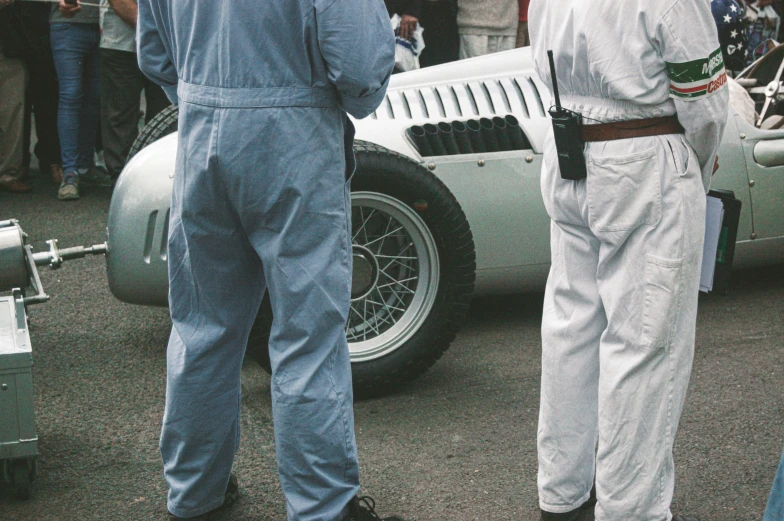 several people looking at a car while others watch