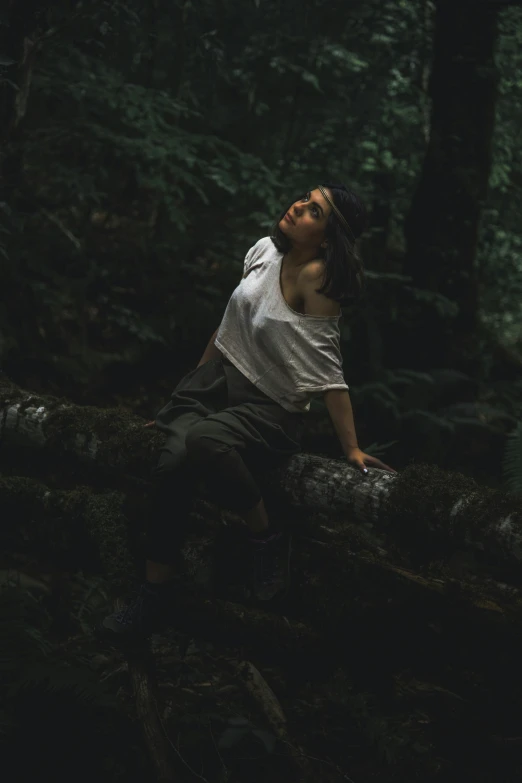 a person standing up in the woods by a fallen tree