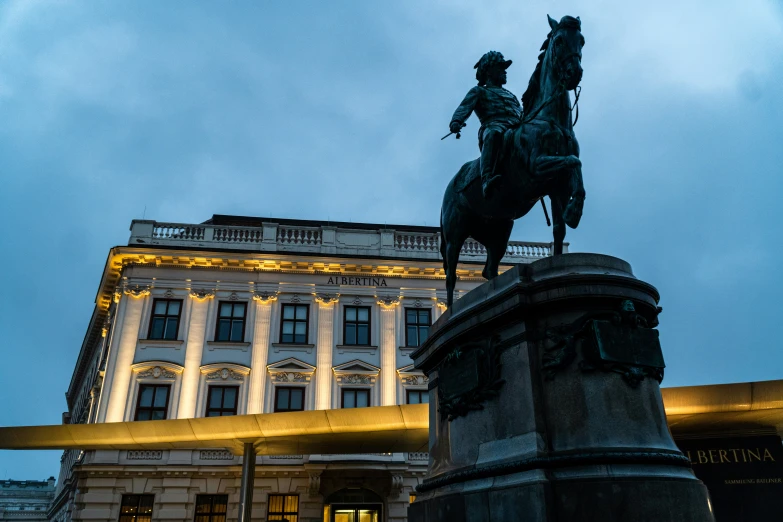 a statue of a man riding a horse near a tall building