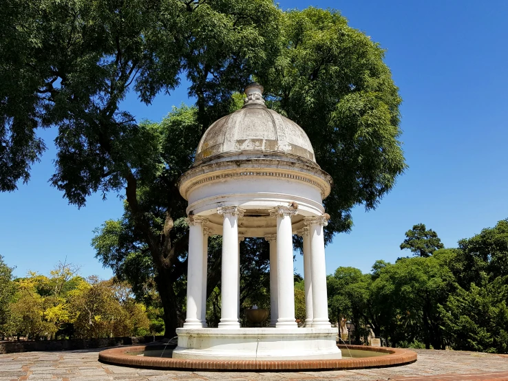 a stone gazebo surrounded by lush green trees