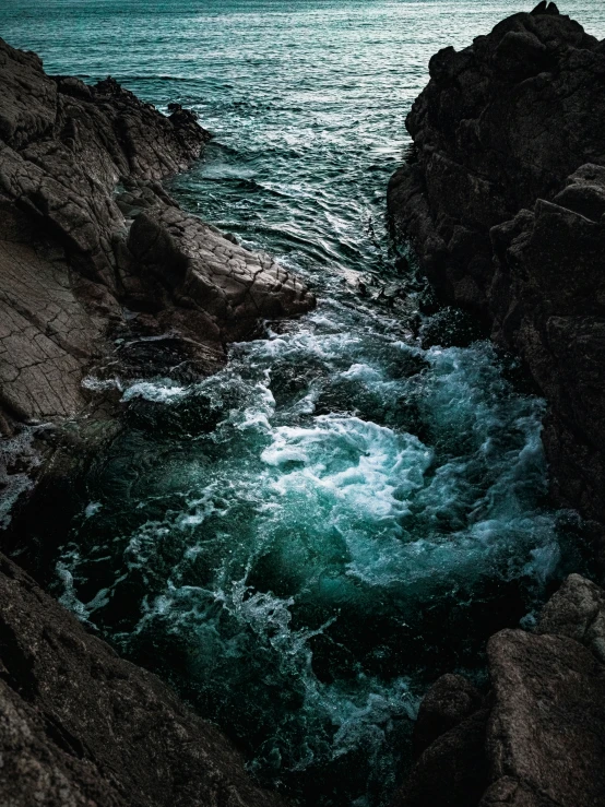 water is crashing against rocks at the edge of a cliff