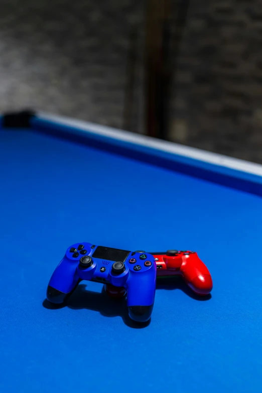 two game controllers sit on a blue cloth