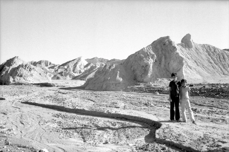 a couple standing in a desert with their arms out