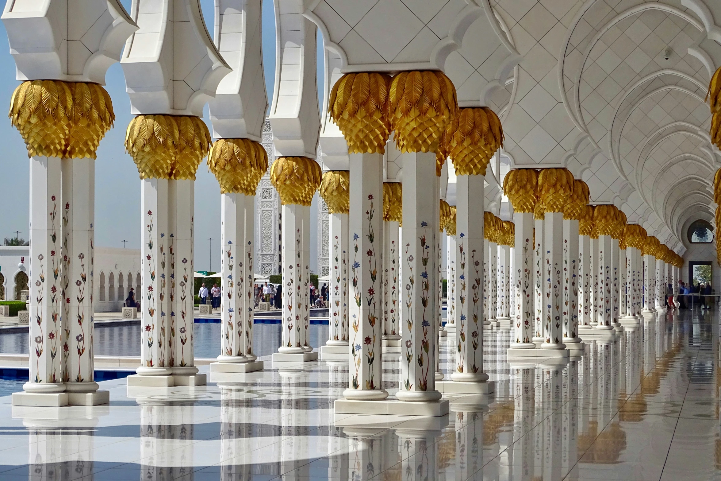 a bunch of white and gold pillars with a sky background