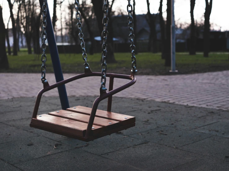 a wooden swing in the park that swings