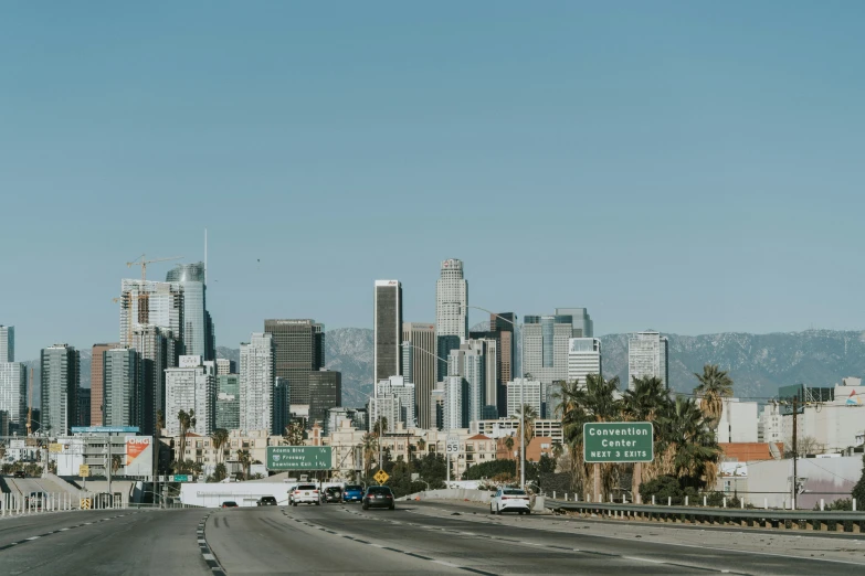 a large city skyline is next to freeway traffic