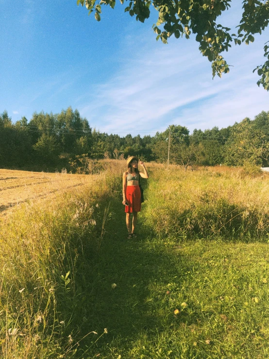 a woman is walking on the grass carrying a hat