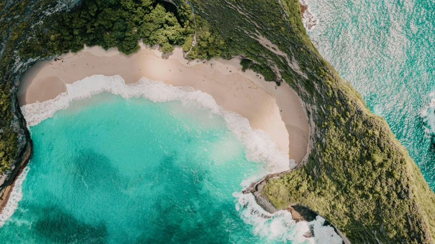 an aerial view of an ocean with a sandy shore and a cove