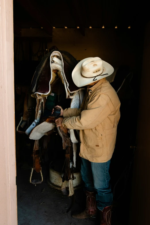 a man wearing a cowboy hat is standing near a horse