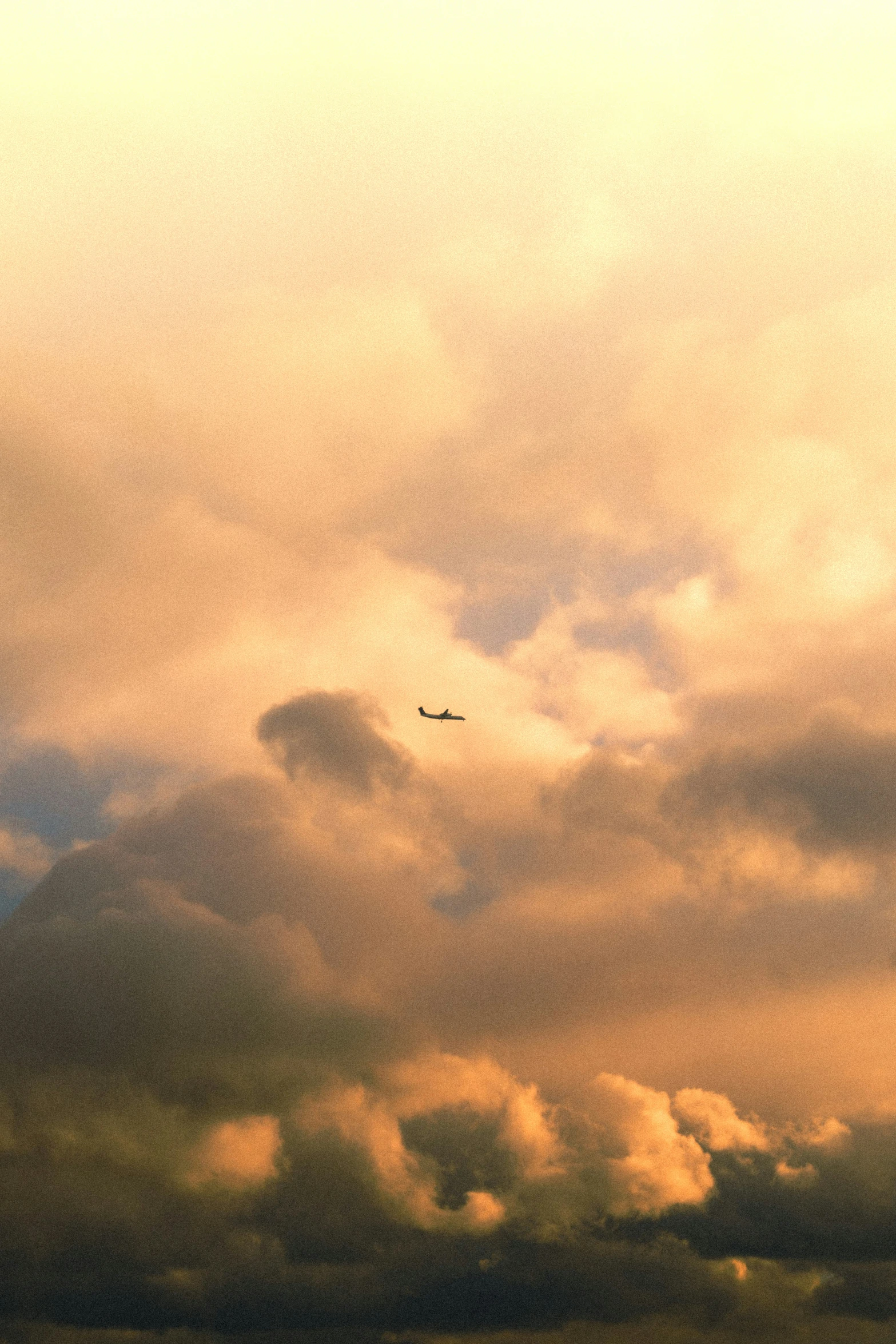 there is a plane flying under the clouds