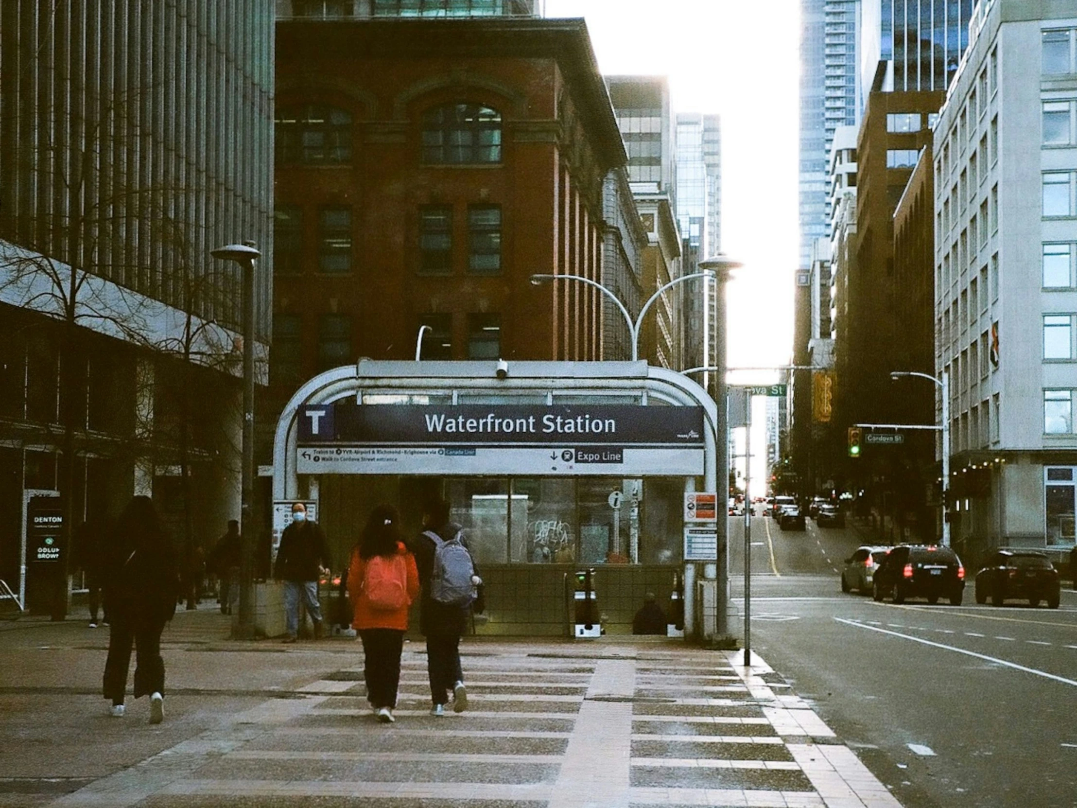 two people walking across the street as a bus passes them