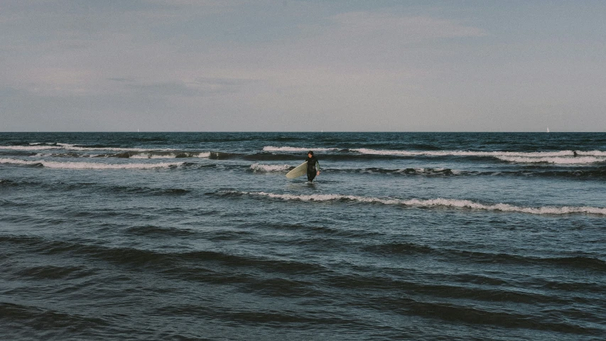 two surfers in the ocean carrying their surf boards