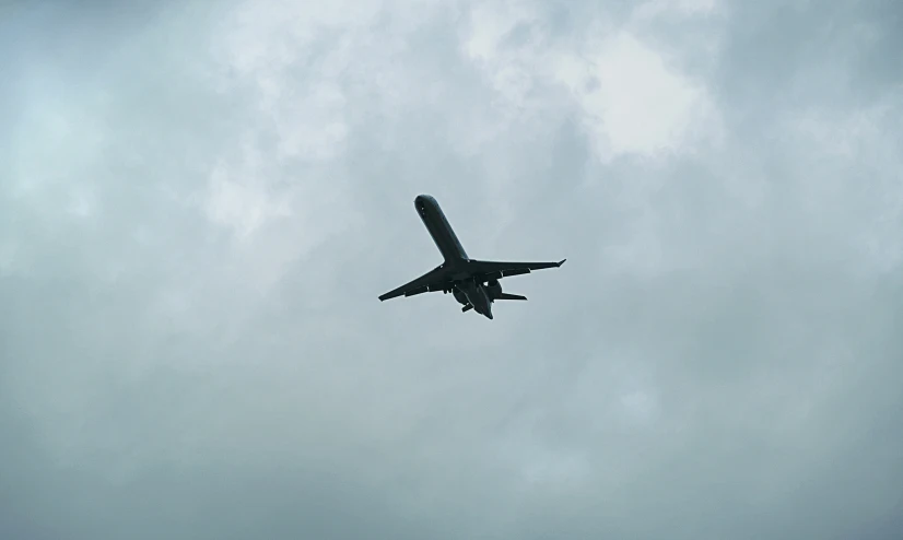 an airplane flying by in the sky, almost covered by some clouds