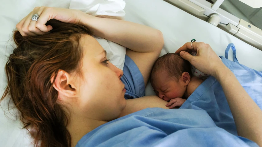 a woman who is laying down with her baby