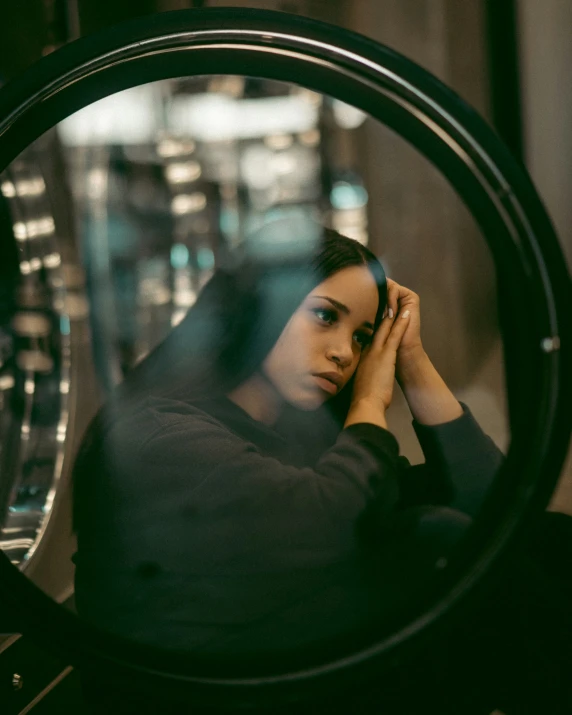 a woman sitting in front of a mirror while looking through