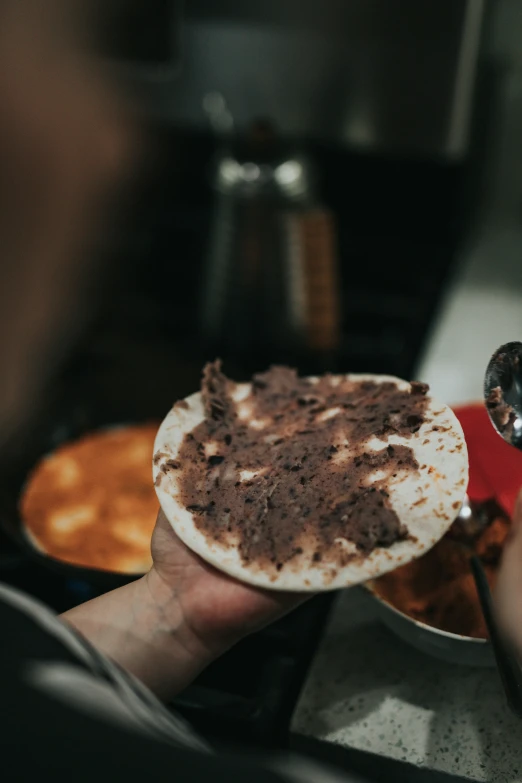 a hand holding a plate with a dessert on it