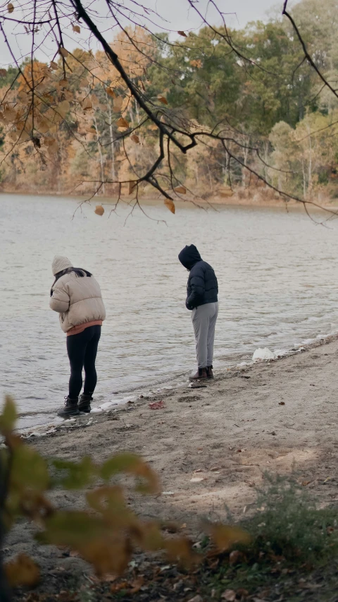 two people standing on the shore of a lake in winter