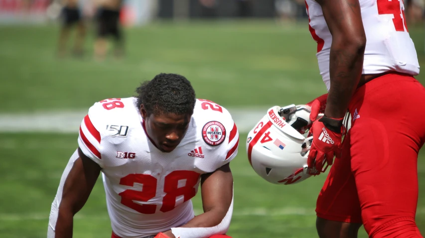 a football player kneels down with his helmet on