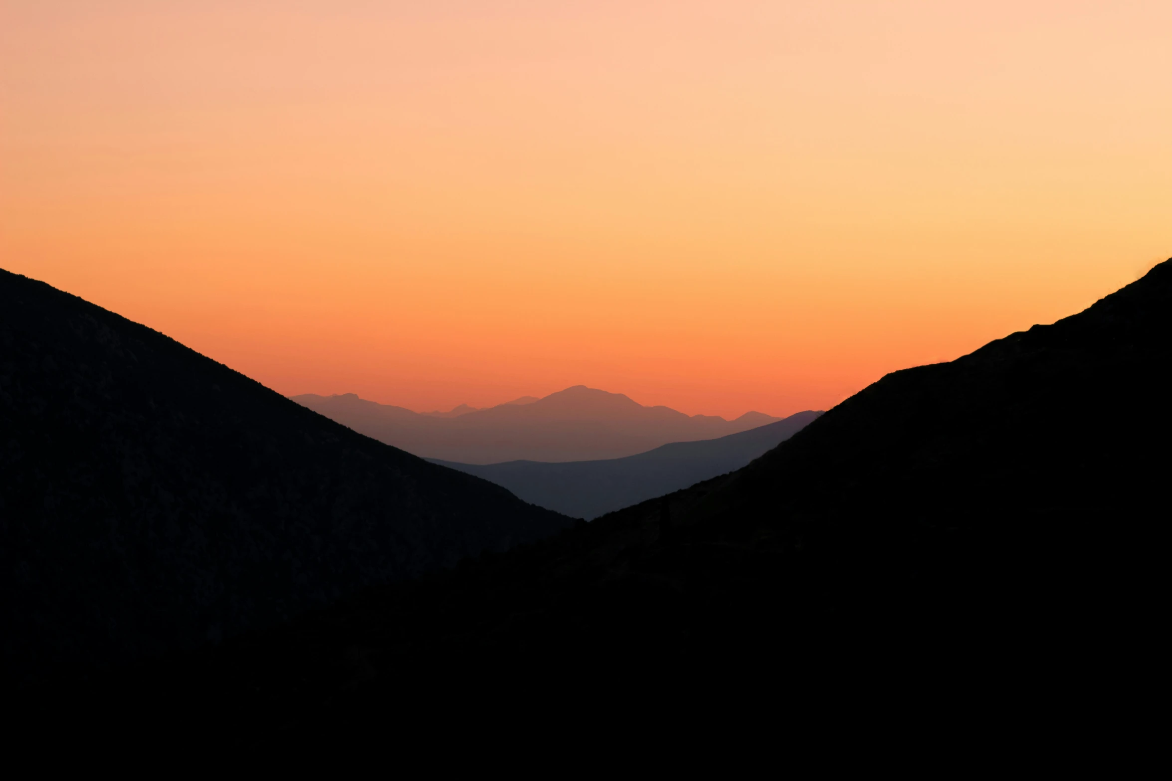 the sunset on the mountains is reflecting the distant sky