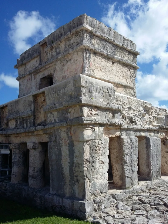 an ancient building sits on a grassy field