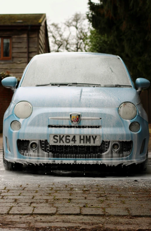 a blue fiat car is parked on a dirty street