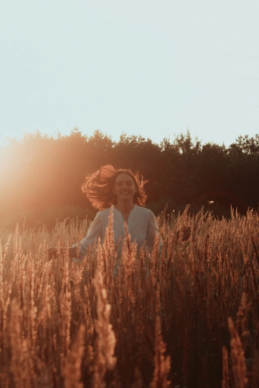 a woman walks through a field with her hair blowing in the wind