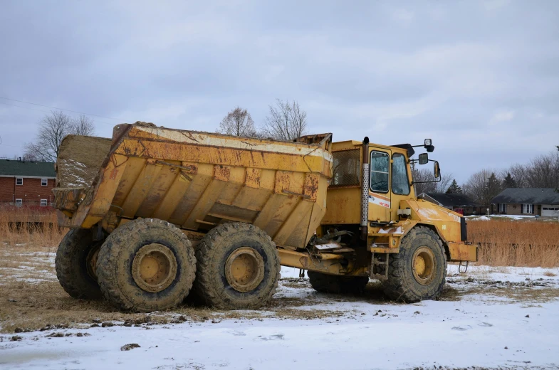 a truck driving across snow covered ground near a yard